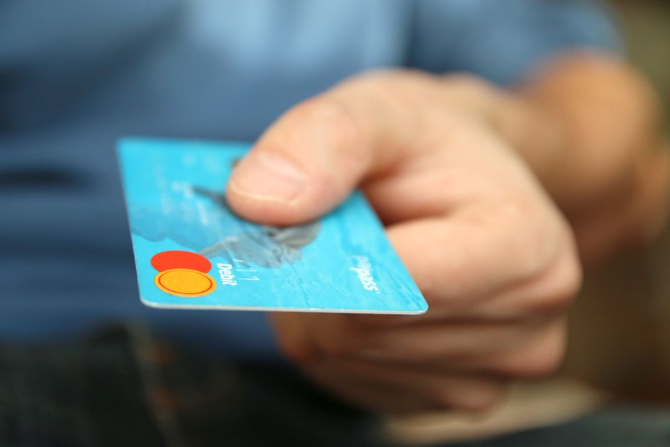 A hand holding out a payment card