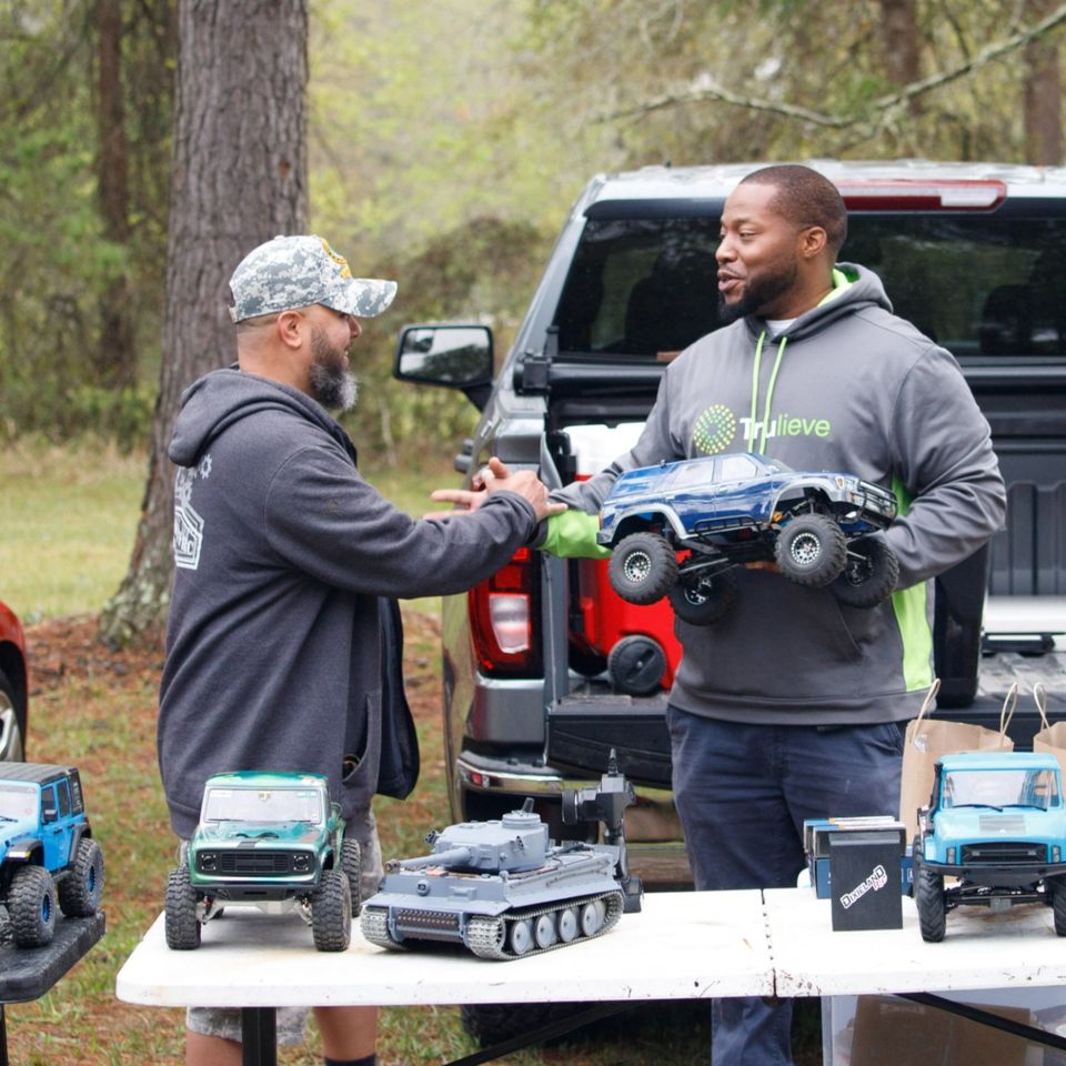 Two members handing over an RC crawler at an O11C outing